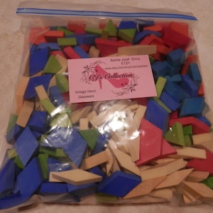 Peut inclure: Un sac en plastique rempli de formes géométriques en bois de différentes couleurs. Les formes sont de différentes tailles et couleurs, notamment bleu, vert, rouge et jaune. Le sac est étiqueté avec le texte "Cfs Collection Vintage Decor Glassware" et une adresse de site Web.