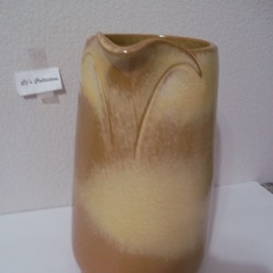 May include: A brown and yellow ceramic pitcher with a wavy rim and a textured design. The pitcher has a light yellow glaze with brown accents.