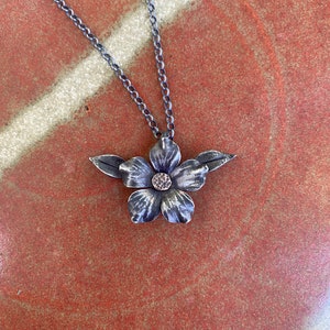 Hand forged iron flower with a pair of leaves pendant with bronze riveted center on sterling chain
