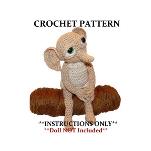 May include: Crochet pattern for a beige amigurumi elephant doll with green eyes. The doll is sitting on a brown ball of yarn. The text "**INSTRUCTIONS ONLY**" and "**Doll NOT Included**" is printed below the doll.
