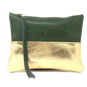 Puede incluir: Una peque&ntilde;a bolsa de cuero verde y dorado con cierre de cremallera. La bolsa tiene una base de cuero dorado y una parte superior de cuero verde. La bolsa tiene una peque&ntilde;a correa de cuero.
