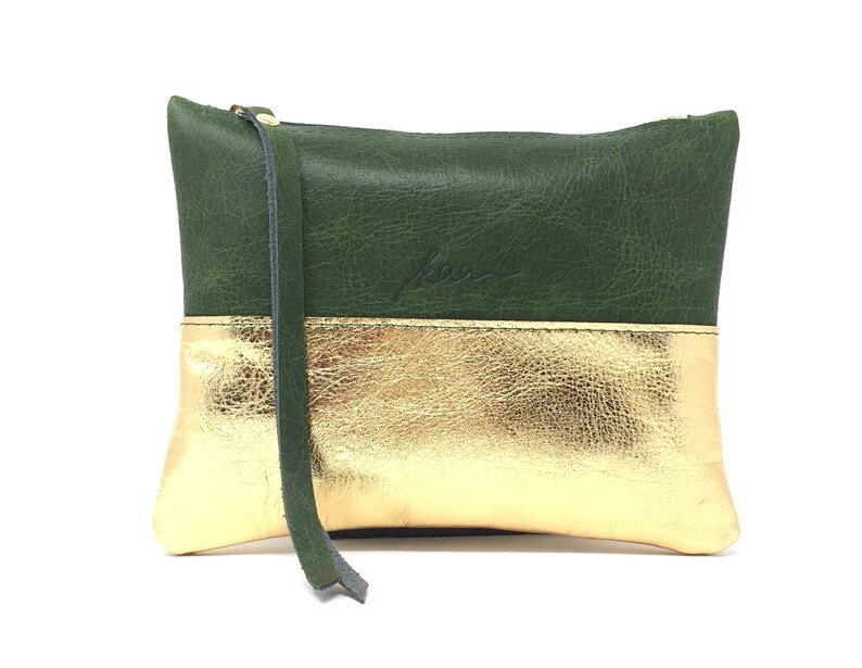 Puede incluir: Una peque&ntilde;a bolsa de cuero verde y dorado con cierre de cremallera. La bolsa tiene una base de cuero dorado y una parte superior de cuero verde. La bolsa tiene una peque&ntilde;a correa de cuero.