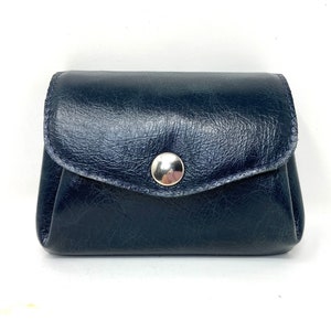May include: A small, dark blue leather coin purse with a silver snap closure.