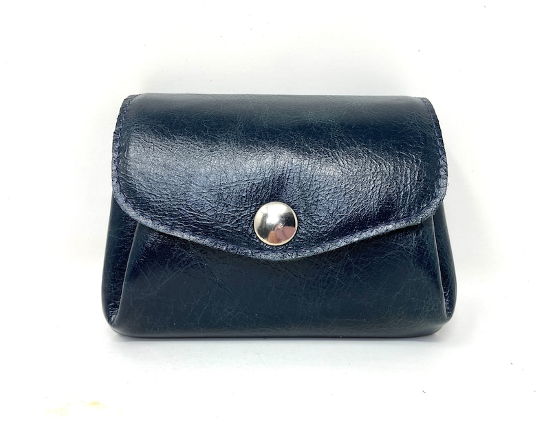 May include: A small, dark blue leather coin purse with a silver snap closure.