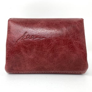May include: A burgundy leather wallet with the word "kao" embossed on the front.