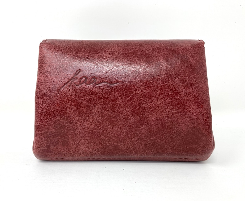 May include: A burgundy leather wallet with the word "kao" embossed on the front.