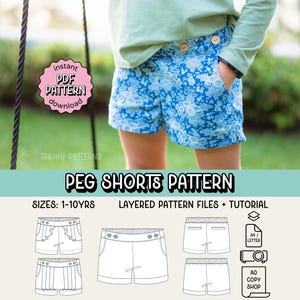 Puede incluir: Pantalones cortos azules con estampado floral y botones de madera. Los pantalones cortos son parte de un patrón de costura para tallas de 1 a 10 años. La imagen también incluye el texto "PEG SHORTS PATTERN" y "instant PDF PATTERN download".