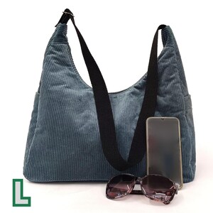 May include: A blue corduroy shoulder bag with a black strap and a phone pocket. The bag has a zipper closure and a top handle.