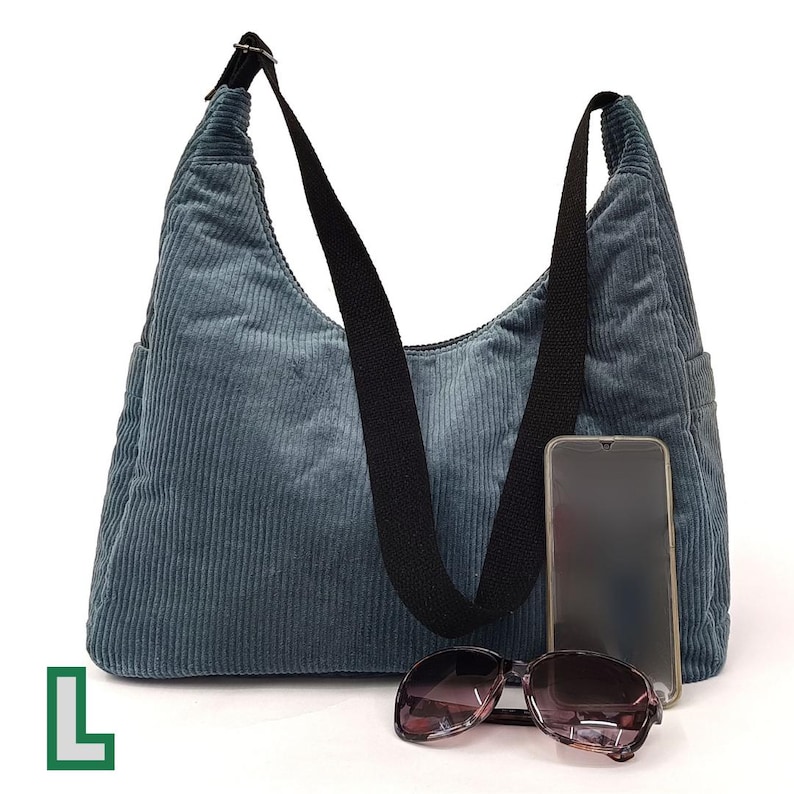 May include: A blue corduroy shoulder bag with a black strap and a phone pocket. The bag has a zipper closure and a top handle.