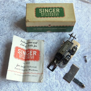 May include: A vintage Singer buttonhole attachment for sewing machines in its original box. The box is white with green and red lettering. The attachment is silver and has a black handle. The instructions are included and are printed on a white sheet of paper with red and black lettering.