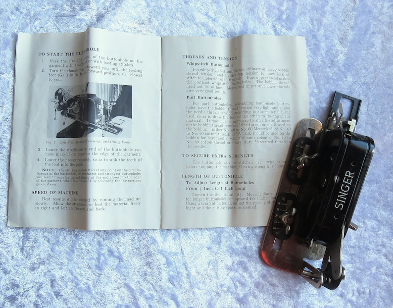 May include: A black Singer buttonhole sewing machine with a metal base and a white instruction booklet. The booklet has instructions on how to use the machine to create buttonholes of different lengths.