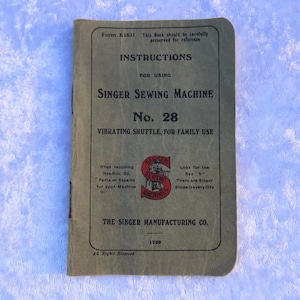 May include: Vintage Singer Sewing Machine No. 28 instruction booklet. The cover is a faded olive green with black text. The Singer logo is red and white. The booklet is from 1920 and includes instructions for family use.