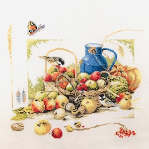 May include: A blue ceramic pitcher with a handle sits in a woven basket filled with red and green apples, a small bird, and a yellow squash. A butterfly is flying above the basket.