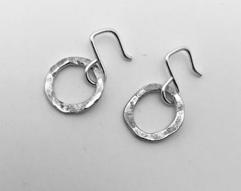 May include: A pair of silver hammered circle earrings with a hook closure.
