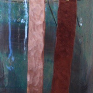 May include: A pair of hammered copper earrings, one is a light pink color and the other is a reddish brown color.