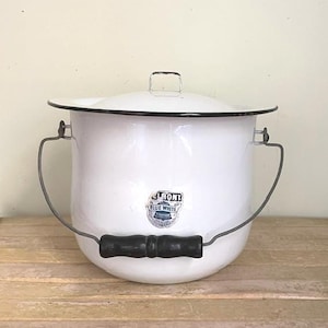 May include: A white enamel bucket with a lid, featuring a black rim and a wire handle with a black wooden grip. A label on the front reads Belmont Blue White Titanium. The bucket has a wide opening and a rounded base for storage.