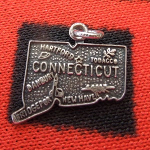 May include: Silver charm shaped like the state of Connecticut with the word "Connecticut" and the names of cities including Hartford, Danbury, Bridgeport, and New Haven.