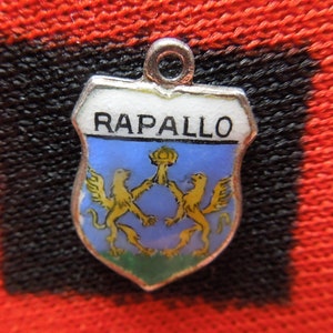May include: A silver charm with a blue and white enamel shield featuring two golden lions and the word "RAPALLO" in white lettering.