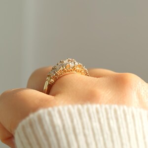 May include: A gold ring with a row of clear gemstones set in a delicate, ornate design.