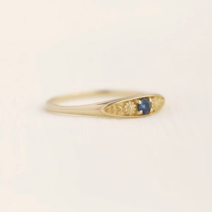Pu&ograve; includere: Un anello d'oro con una pietra preziosa blu e dettagli floreali.