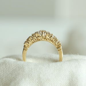 May include: A gold band ring with a row of small diamonds set in a delicate, intricate design.