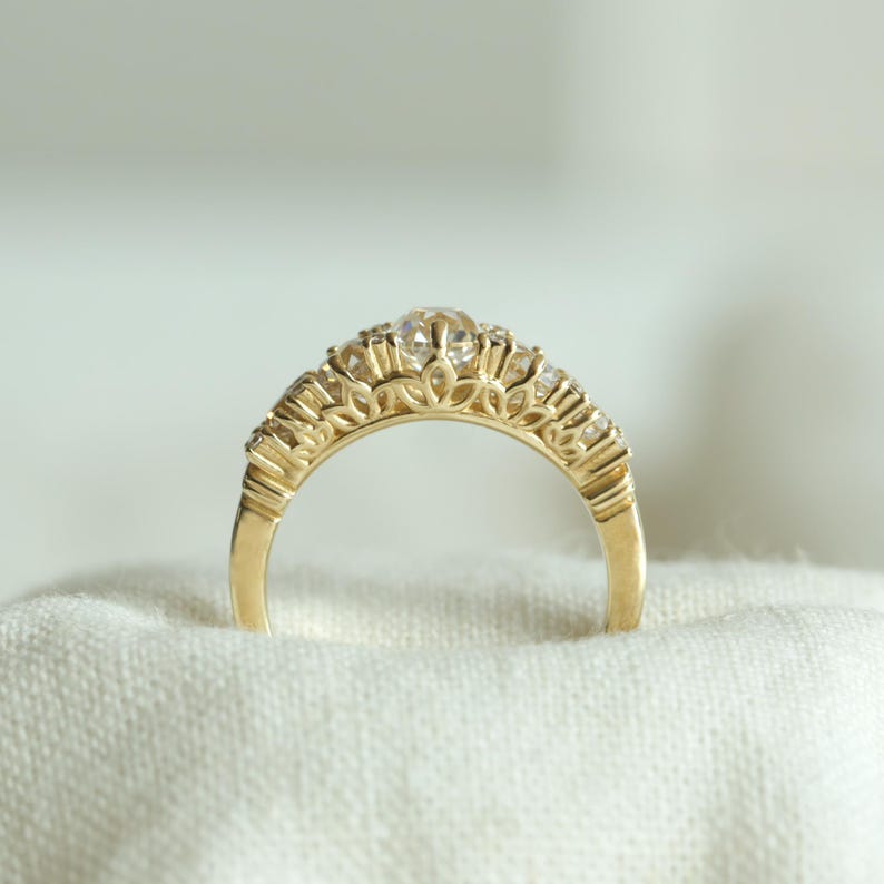 May include: A gold band ring with a row of small diamonds set in a delicate, intricate design.