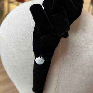 Puede incluir: Diadema de terciopelo negro con una etiqueta de metal plateado que dice "BOZKA".