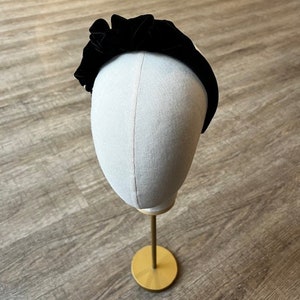 Puede incluir: Diadema de terciopelo negro con un dise&ntilde;o fruncido y con volantes. La diadema se muestra en una cabeza de maniqu&iacute;.