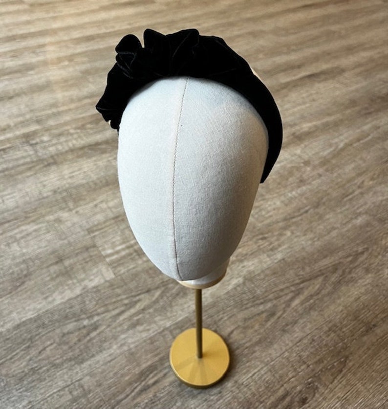 Puede incluir: Diadema de terciopelo negro con un dise&ntilde;o fruncido y con volantes. La diadema se muestra en una cabeza de maniqu&iacute;.