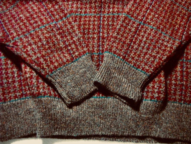 May include: A red, blue and grey patterned sweater with a ribbed knit cuff and hem.