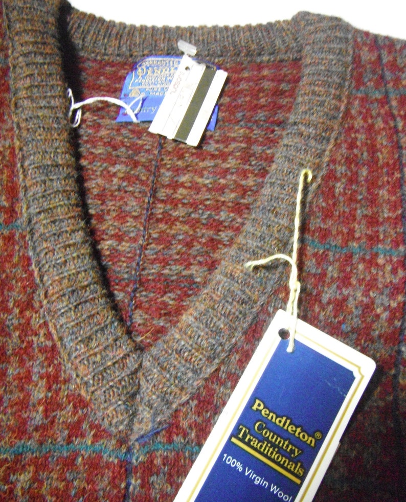 May include: A Pendleton Country Traditionals V-neck sweater in a red, brown and blue plaid pattern. The tag reads "Pendleton Country Traditionals 100% Virgin Wool".