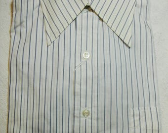 May include: A white dress shirt with thin blue stripes. The shirt has a button-down collar and a single pocket on the left side. The brand name "Sulka" is visible on the collar.