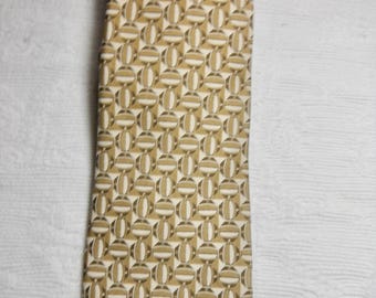 May include: A gold and white patterned tie with a geometric design.