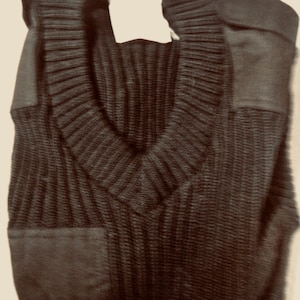 Może przedstawiać: Brązowy sweter z dzianiny z dekoltem w kształcie litery V i naszywką po lewej stronie.