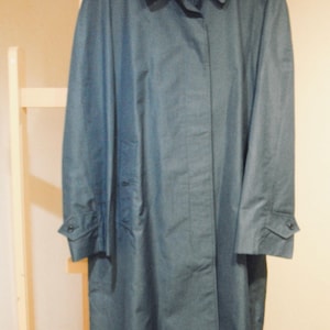 Puede incluir: Un abrigo largo de color azul oscuro con cierre de botones y cuello. El abrigo tiene un solo botón en cada puño.