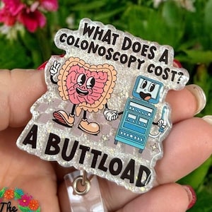 May include: A silver glitter badge holder with a cartoon intestine and medical machine. The text reads "What does a colonoscopy cost? A buttload."