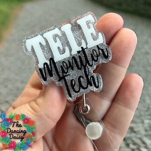 May include: A silver glitter badge holder with a white "TELE MONITOR TECH" text. The badge holder has a clear plastic retractable reel.