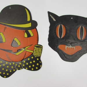May include: Two vintage Halloween decorations: a black cat with orange eyes and a pumpkin wearing a black top hat and bow tie, holding a pipe.