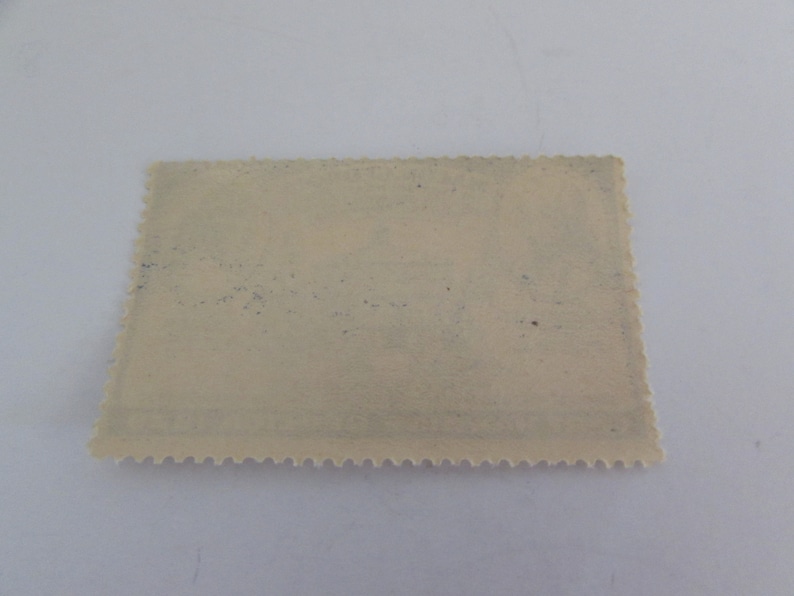 May include: A blank, off-white postage stamp with a scalloped edge. The stamp has a faint blue tint and some light brown spots.