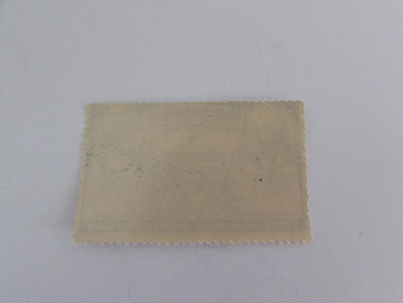 May include: A vintage postage stamp with a faded design and a scalloped edge.