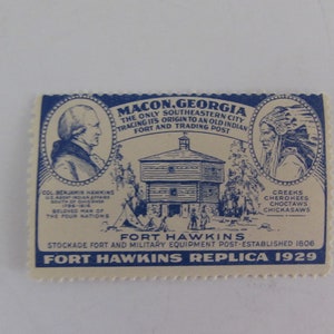 May include: A blue and white vintage stamp commemorating Fort Hawkins in Macon, Georgia. The stamp features a drawing of the fort, a portrait of Col. Benjamin Hawkins, and a portrait of a Native American. The text on the stamp reads "Macon, Georgia, The Only Southeastern City Tracing Its Origin to an Old Indian Fort and Trading Post", "Fort Hawkins", "Stockade Fort and Military Equipment Post-Established 1806", and "Fort Hawkins Replica 1929".