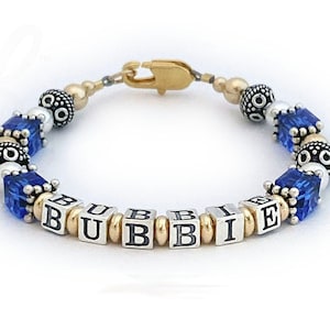 May include: A blue and silver beaded bracelet with gold spacers and the name "BUBBIE" spelled out in silver block letters.
