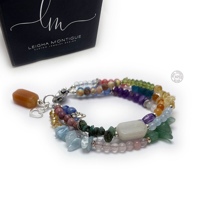 Multi-strand bracelet featuring a variety of colorful gemstones, including amethyst, rose quartz, aquamarine, and citrine. The bracelet has a silver clasp and a heart charm.