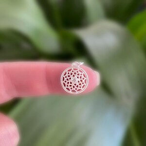 May include: Silver pendant featuring a detailed mandala design with a clear crystal in the center.