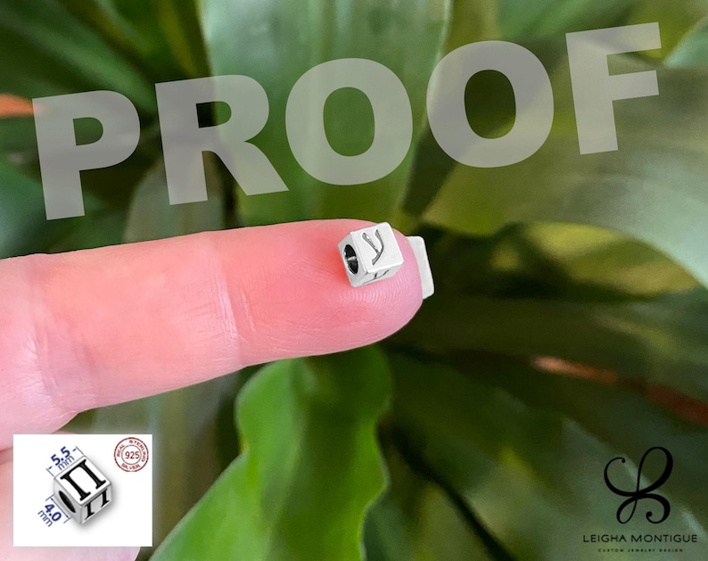 May include: A small silver cube-shaped bead featuring a black engraved Greek letter pi on its side. The bead has a central hole for threading. An inset diagram shows the bead measures 5.5 mm by 4.0 mm and includes a 925 sterling silver stamp.