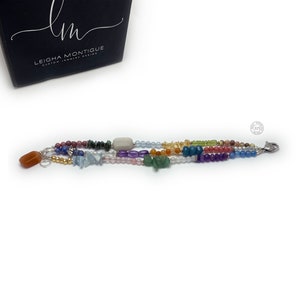 Multi-strand bracelet featuring a variety of colorful gemstones, including amethyst, rose quartz, aquamarine, and citrine. The bracelet has a silver clasp and a heart charm.