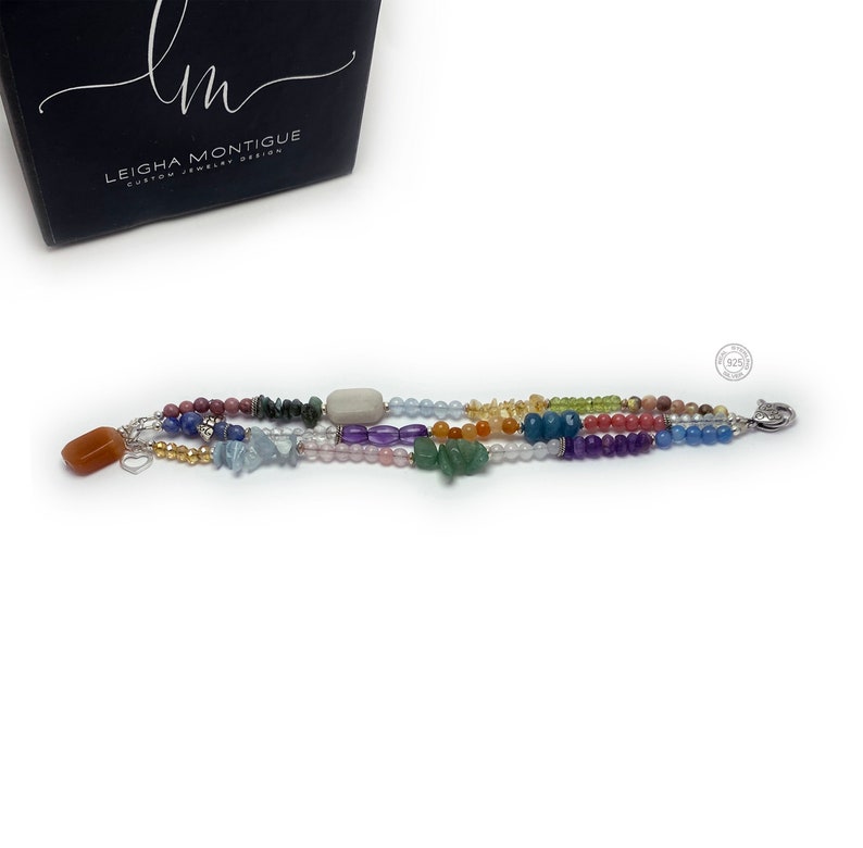 Multi-strand bracelet featuring a variety of colorful gemstones, including amethyst, rose quartz, aquamarine, and citrine. The bracelet has a silver clasp and a heart charm.