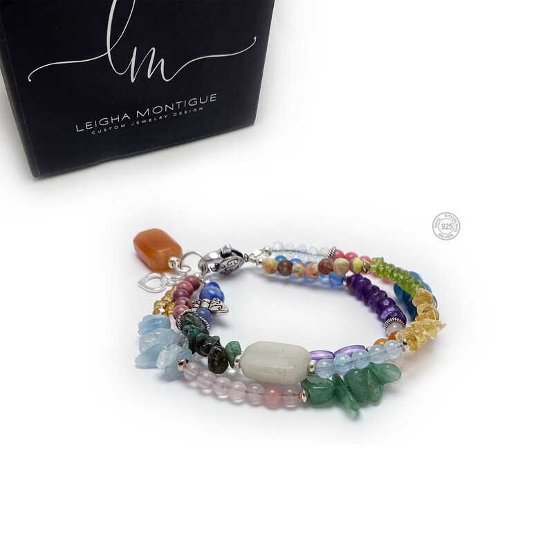 Multi-strand bracelet featuring a variety of colorful gemstones, including amethyst, rose quartz, aquamarine, and citrine. The bracelet has a silver clasp and a heart charm.