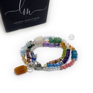 Multi-strand bracelet featuring a variety of colorful gemstones, including amethyst, rose quartz, aquamarine, and citrine. The bracelet has a silver clasp and a heart charm.