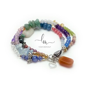 Multi-strand bracelet featuring a variety of colorful gemstones, including amethyst, rose quartz, aquamarine, and citrine. The bracelet has a silver clasp and a heart charm.